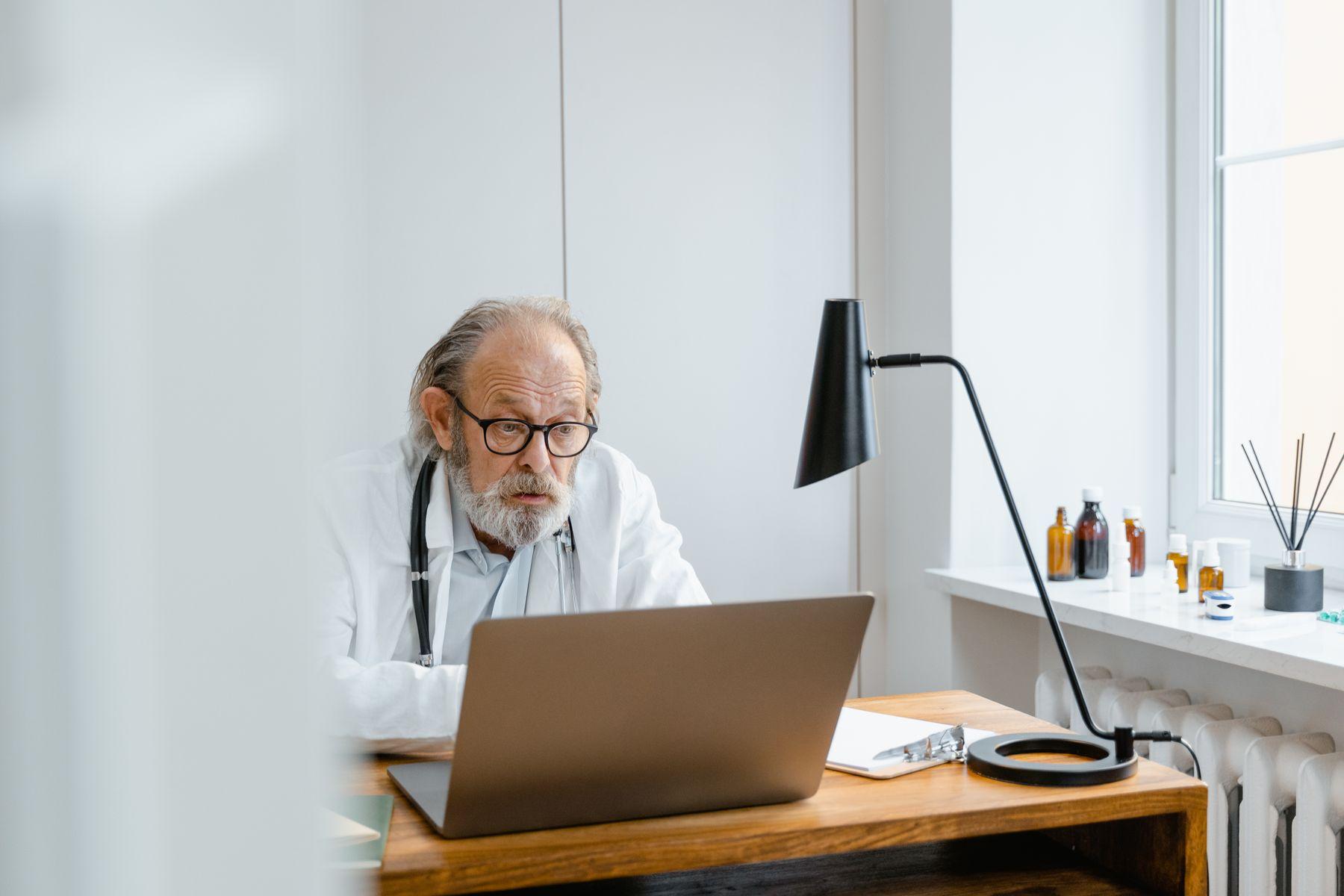 A doctor working on a laptop in a consultation room